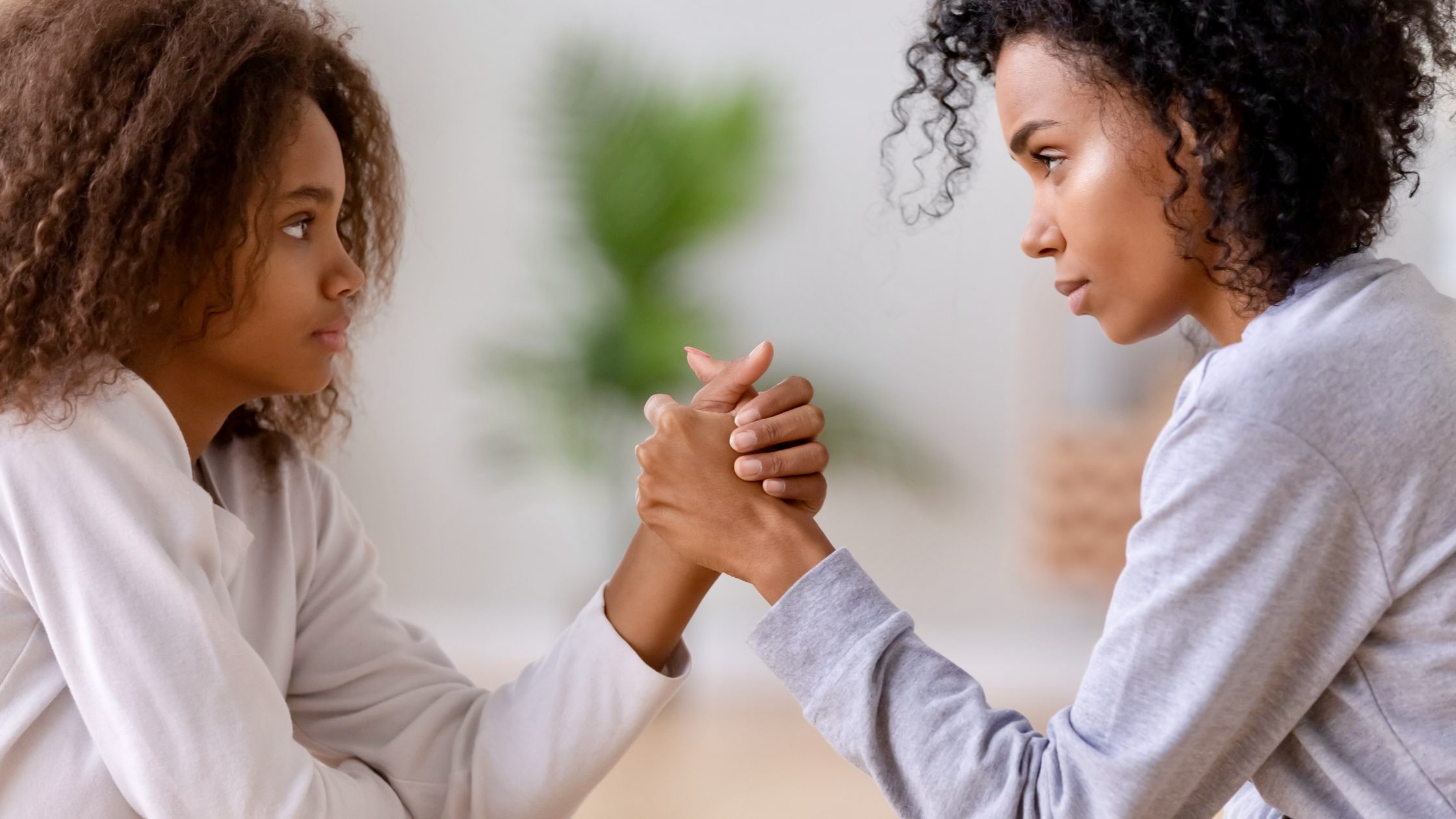 mom and teenage daughter arm wrestling